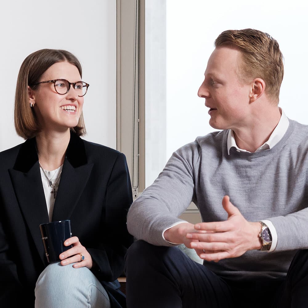 Kollegin und Kollege im entspannten Gespräch im modernen Büro