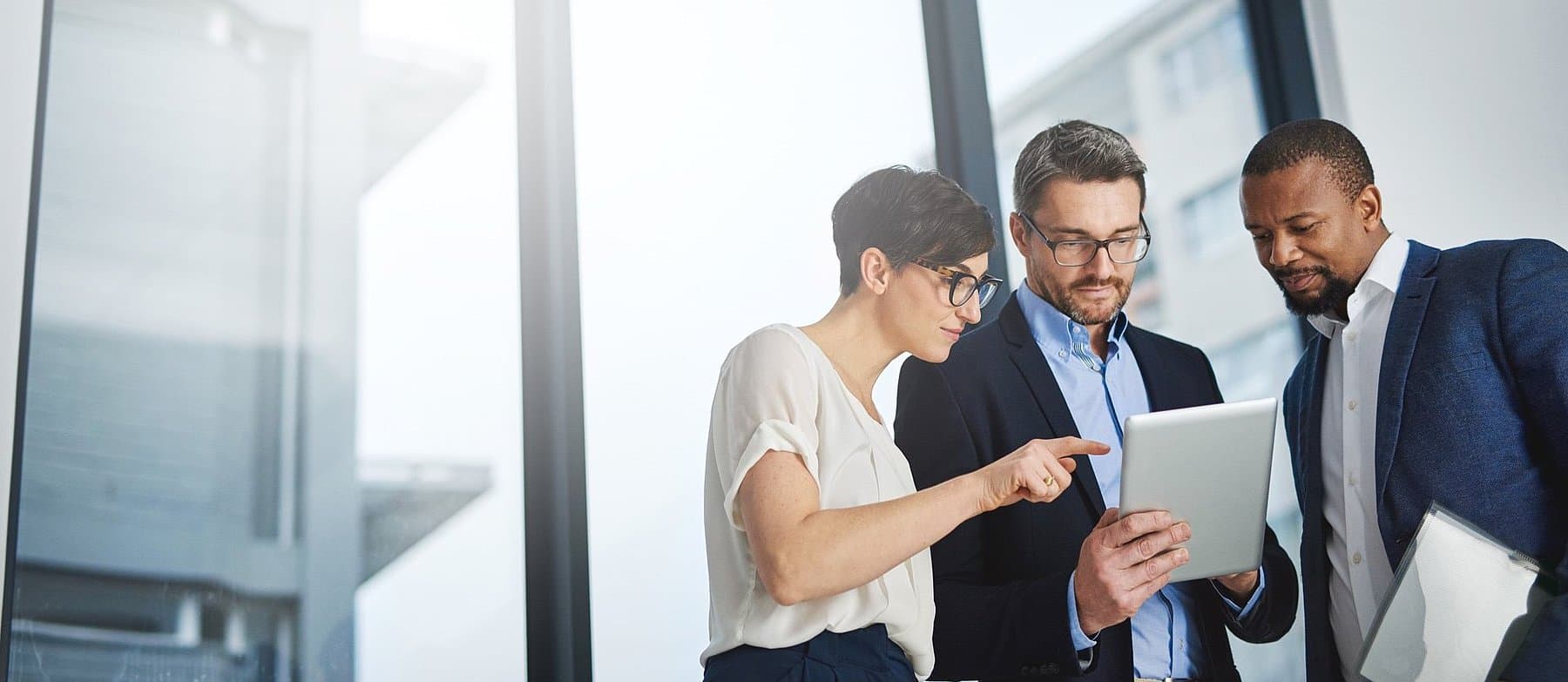 Eine Beraterin und zwei Berater besprechen Inhalte auf einem Tablet