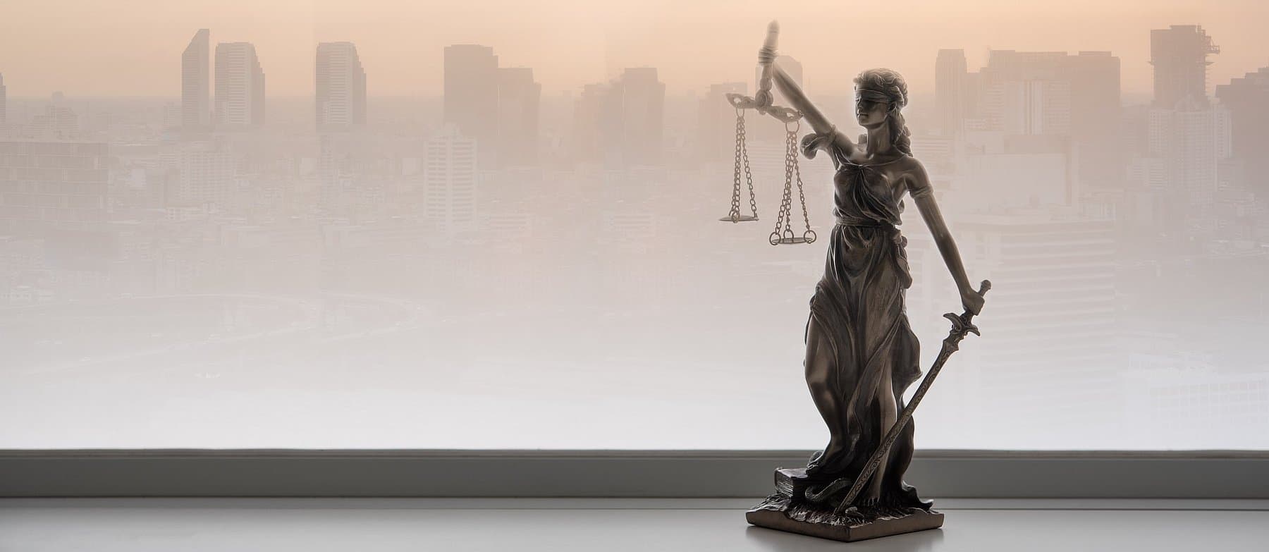 Justitia-Statue vor der Skyline einer Großstadt